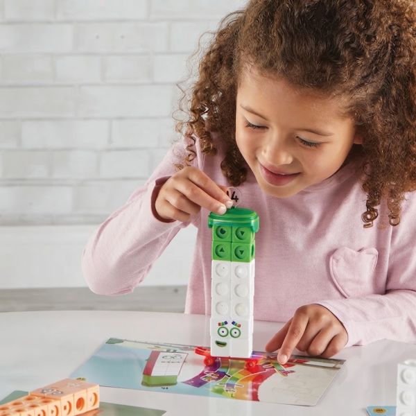A young girl playing with the numberblocks 11 20 activity set while placing number 14 on a block