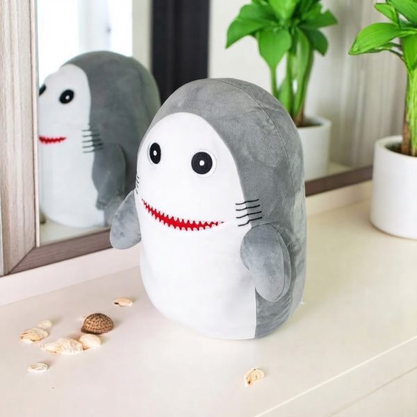 Kobioto Shark Supersoft Plush toy sitting on a table with a mirror reflection and plants in the background